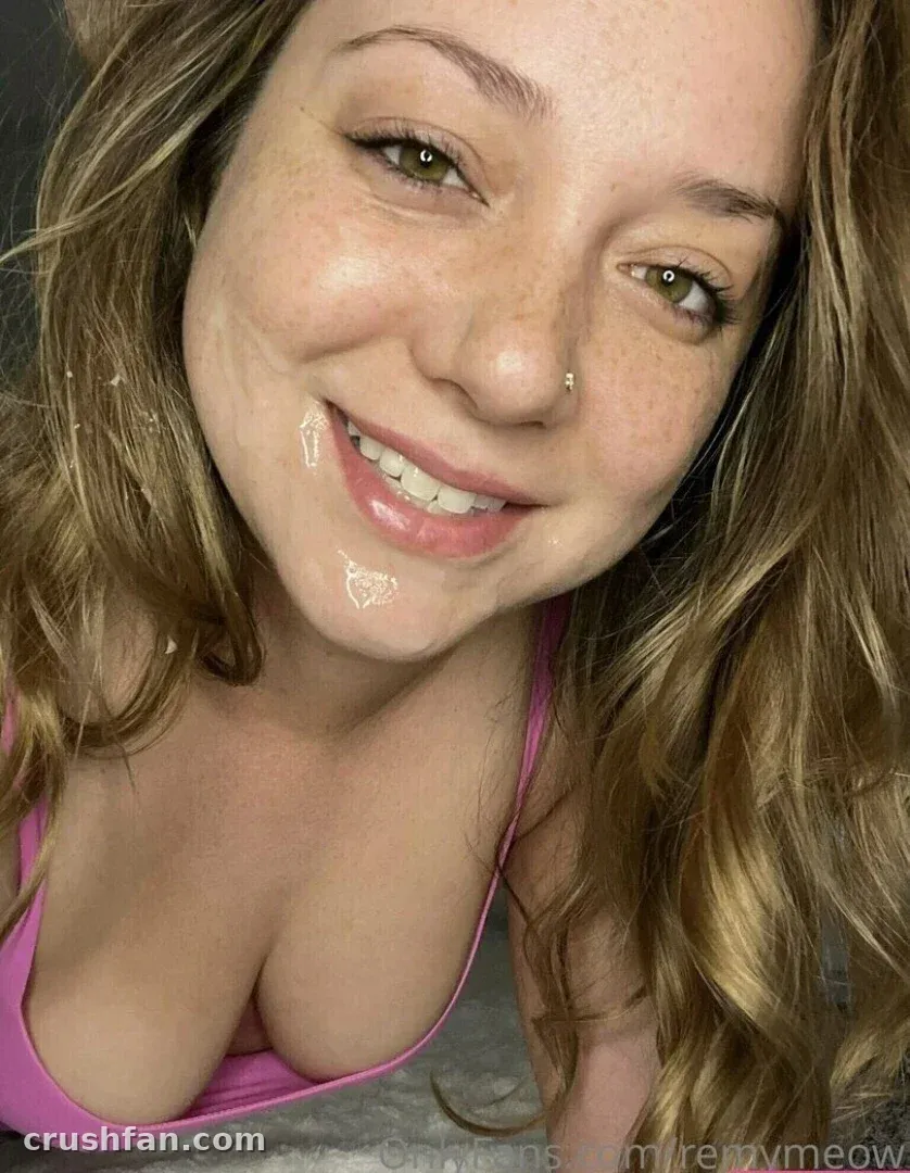 Close-up selfie of Remy LaCroix smiling, wearing a pink top, with wavy blonde hair around her face.