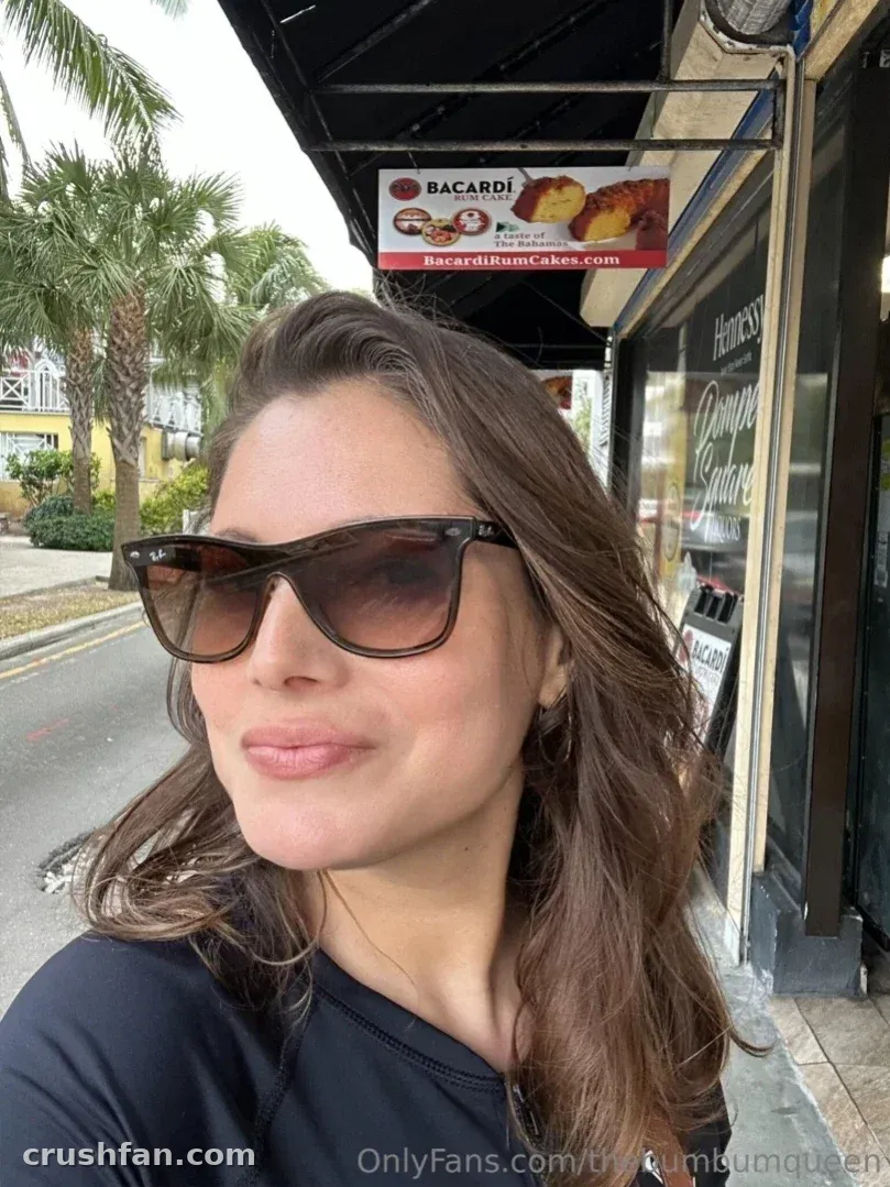 TheBumbumqueen usando óculos escuros ao ar livre em uma esquina de rua.