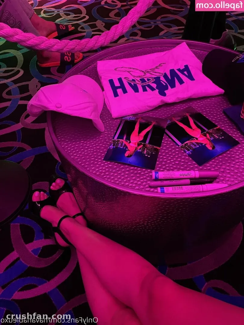 Legs resting near a table with a pink shirt and cards under bright pink neon light