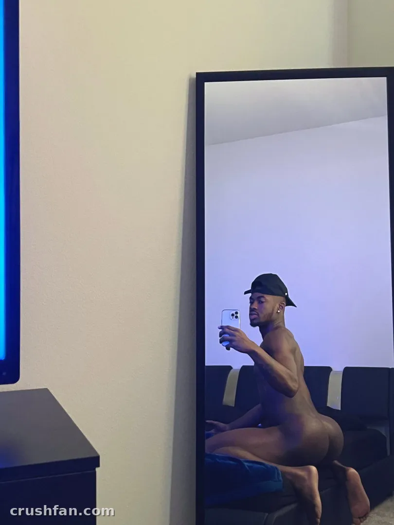 Future X takes a mirror selfie while crouching on a dark sofa in a dim room.