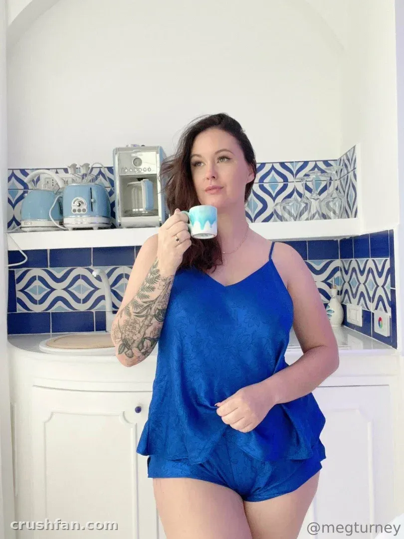 Meg Turney VIP in a blue camisole holding a mug in a blue and white tiled kitchen.