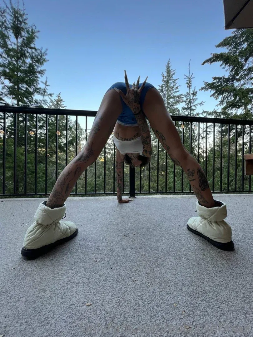 Keaton Belle bends forward on an outdoor deck wearing a blue top and white winter boots.