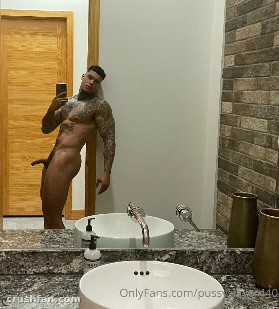 DOMINATOR taking a mirror selfie in a bathroom with a granite counter and stone wall.