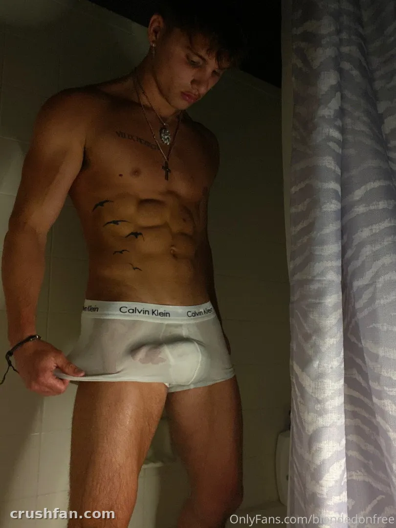 Creator in white briefs standing in a dim bathroom beside a shower curtain