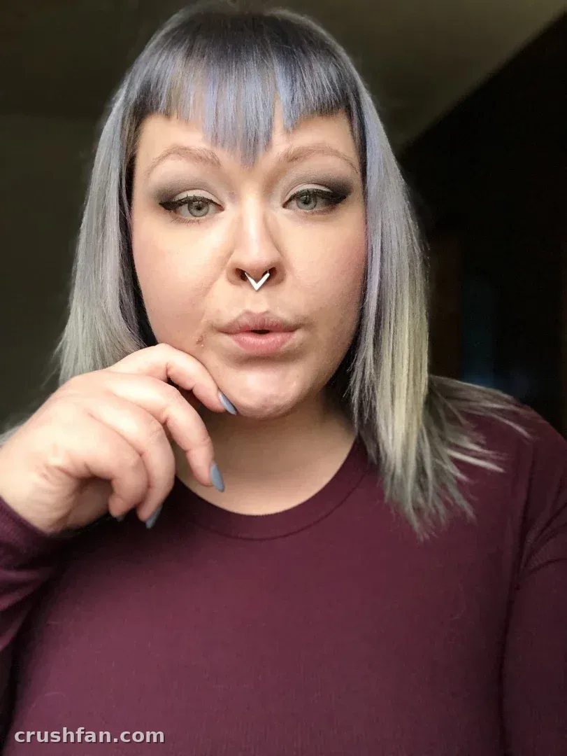 Close-up selfie of Mcjigglezzz in a burgundy top with grey hair and a septum ring.