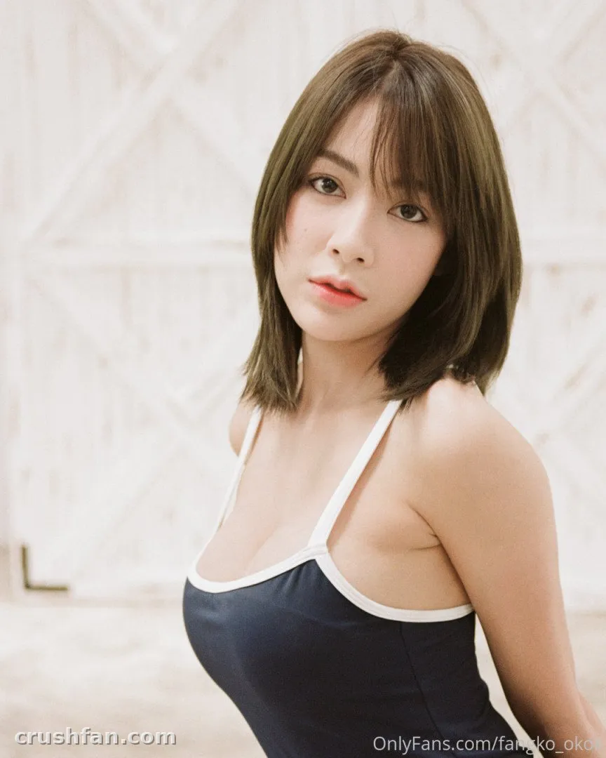 Fangko in a dark swimsuit with white trim against a white background.