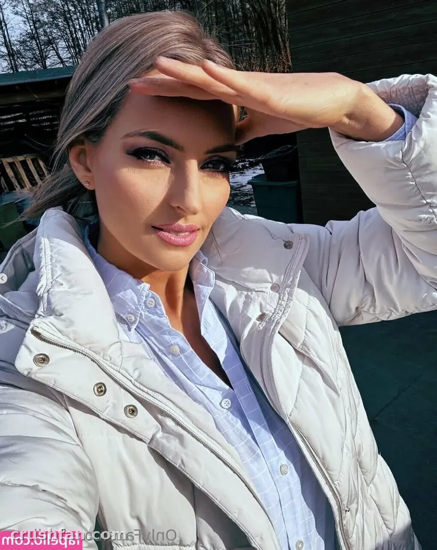Creator in a light quilted jacket and blue shirt shielding her eyes outdoors