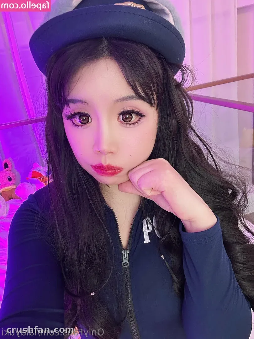 Yuki mit dunkelblauer Cap und Zip-Top posiert unter pinkem und violettem Licht.