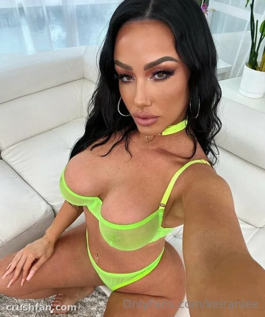 Créatrice dans un ensemble deux pièces vert néon assise sur un canapé blanc en intérieur