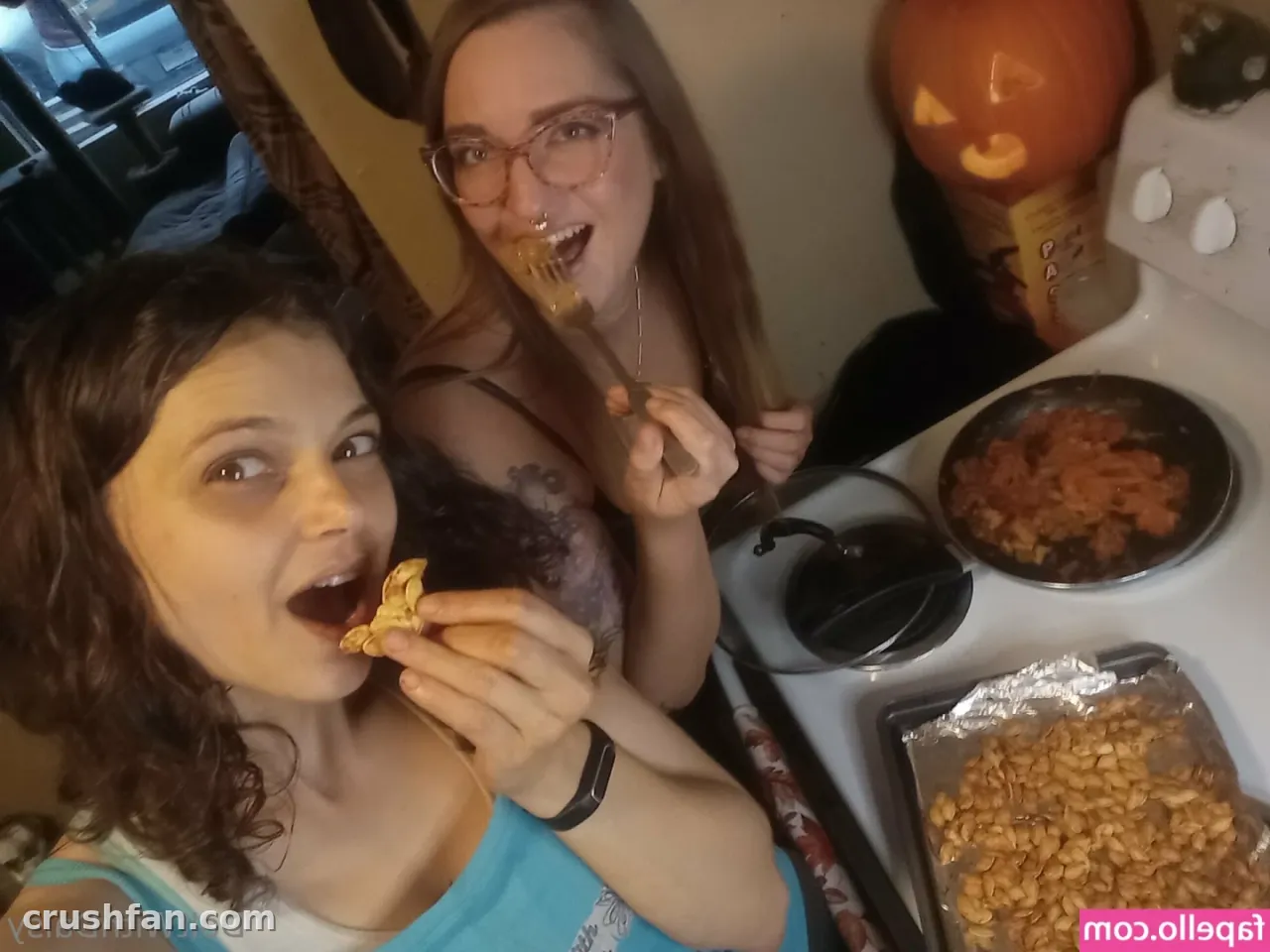 Two people smiling in a kitchen with a carved pumpkin and snacks on the stove