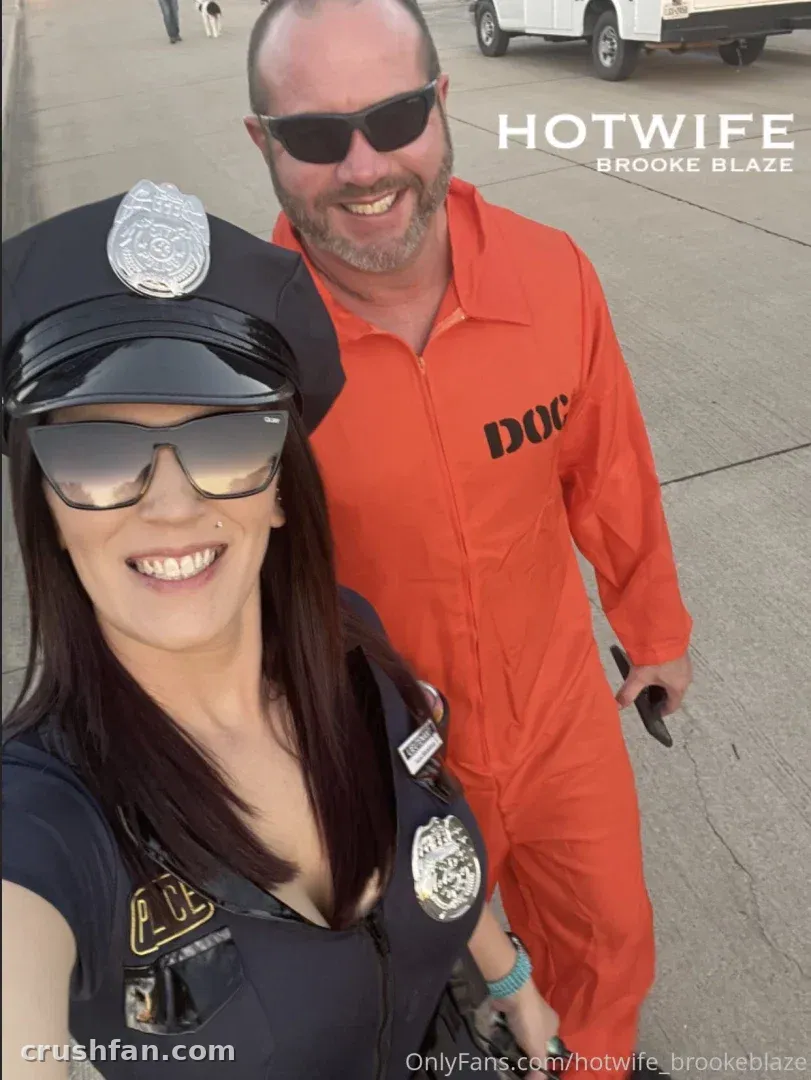 Hotwife Brooke Blaze en costume de policière posant en extérieur avec une personne en combinaison orange.