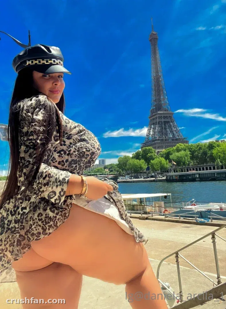Creator in a leopard-print top and cap posing outdoors with a tall tower in the background