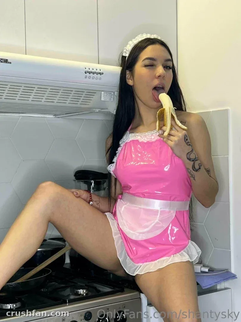 Shantal Sky in a pink apron holding a banana in a kitchen