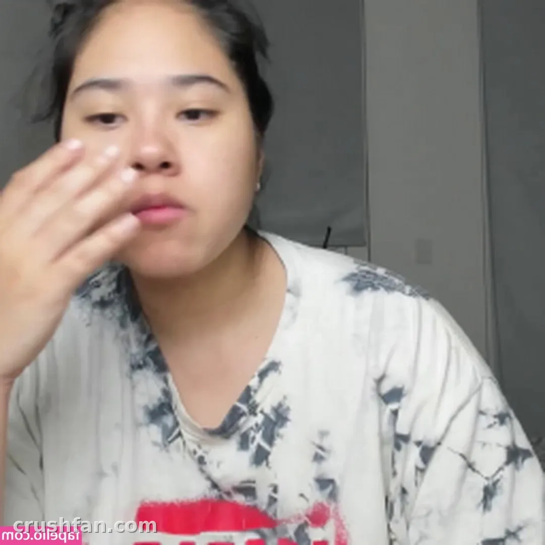 Créatrice dans un haut blanc en tie-dye levant une main près de son visage à l'intérieur