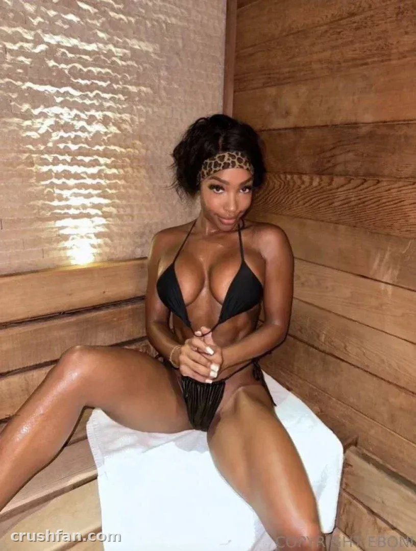 Hannah in einem schwarzen Bikini und Leoparden-Stirnband auf einem Handtuch in einer Holzsauna