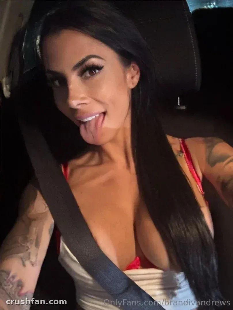Brandi Andrews taking a playful selfie inside a car while wearing a red top
