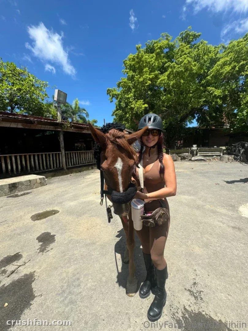 Dani ♥️ in a helmet and sunglasses standing beside a brown horse outdoors