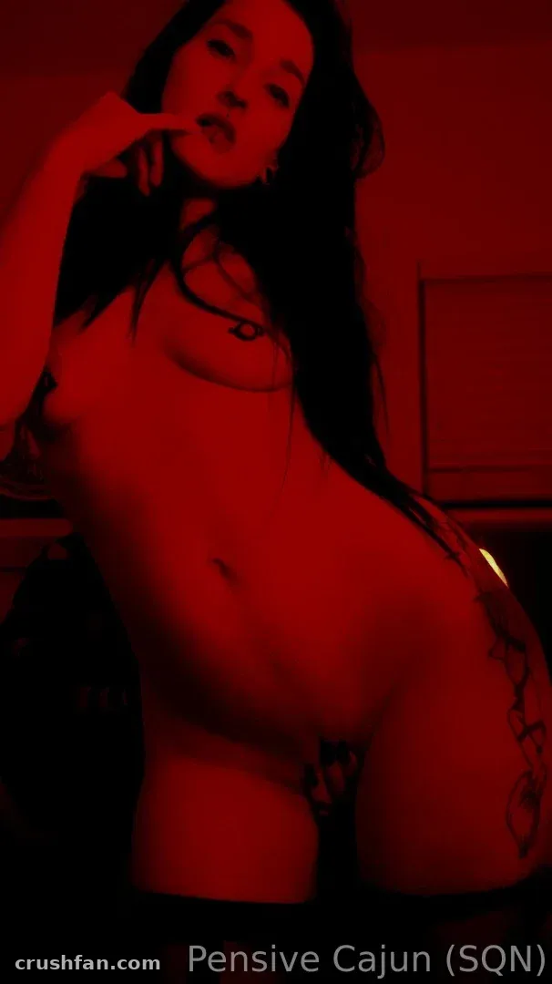 Freya posando en interiores bajo una luz roja intensa con cabello oscuro y un collar