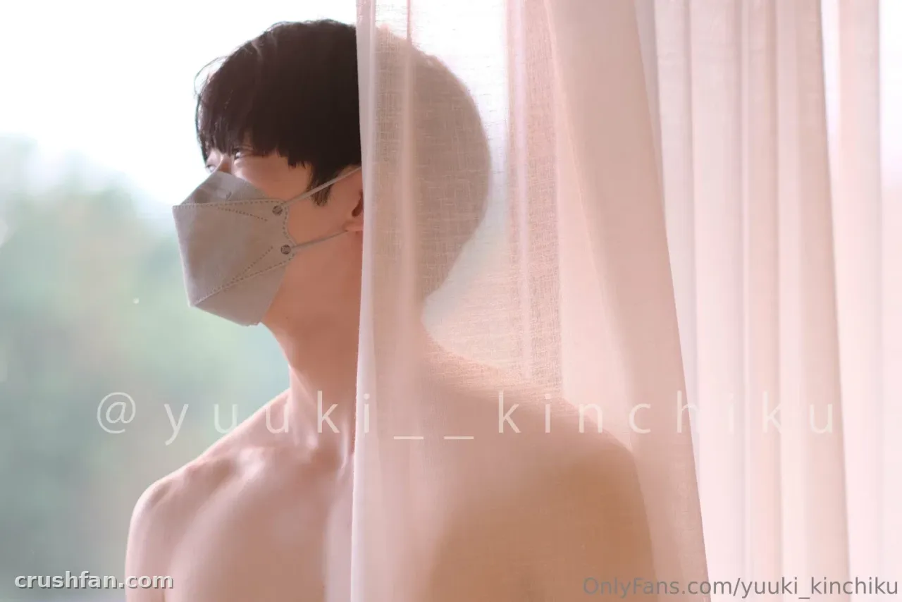 Yuuki in a face mask beside a bright window with a sheer curtain
