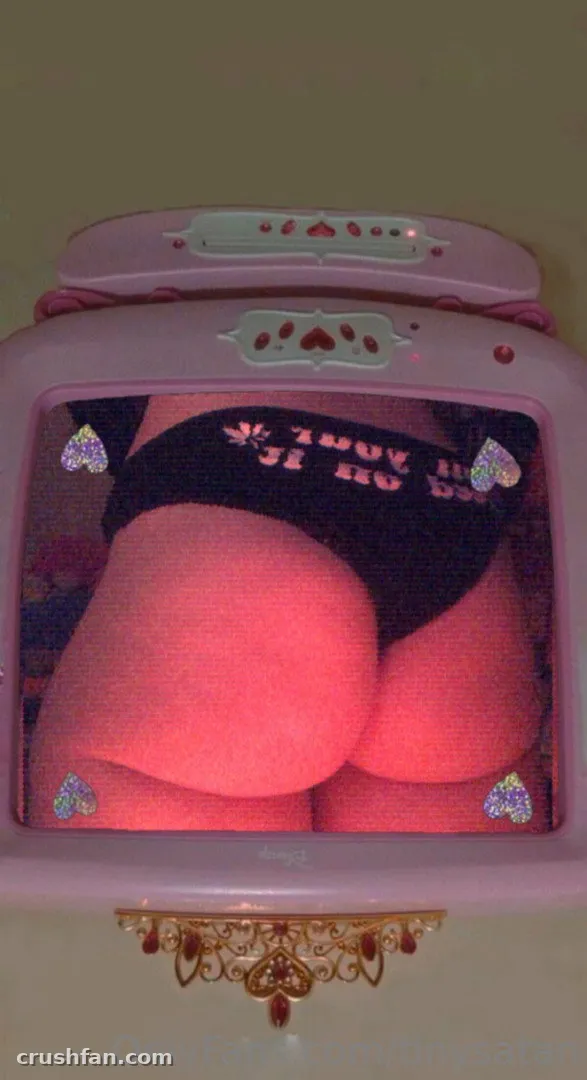 Tiny Satan in black underwear under pink light inside a pink frame.