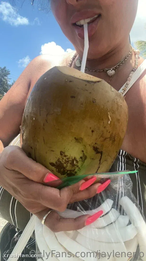 Jaylene Rio holds a green coconut with a straw on a sunny day.