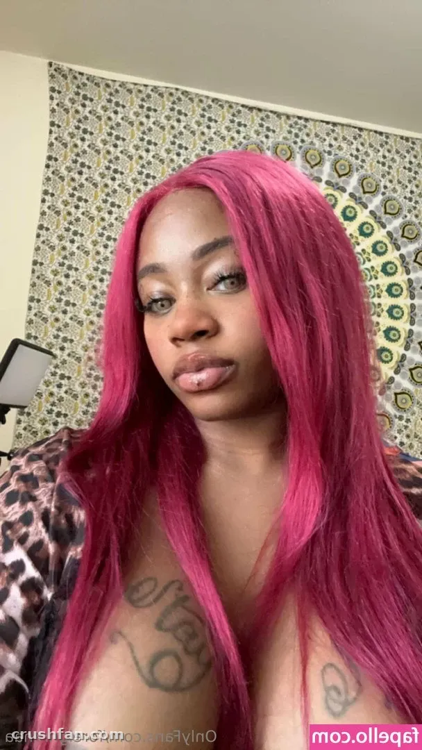 Creadora con cabello largo rosa y un top de estampado de leopardo frente a un tapiz de pared estampado