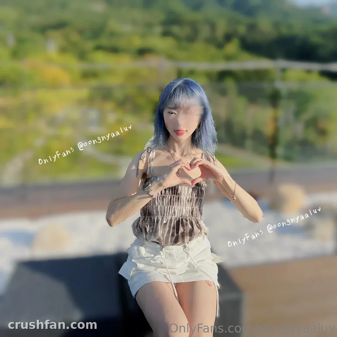 김웅냐 outdoors in a striped top and white skirt making a heart with her hands