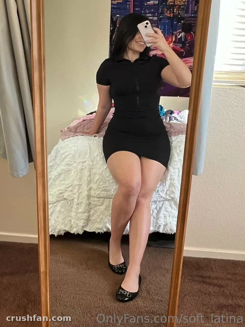 Ingrid Gonzalez con un vestido negro tomándose una selfie en el espejo en un dormitorio.