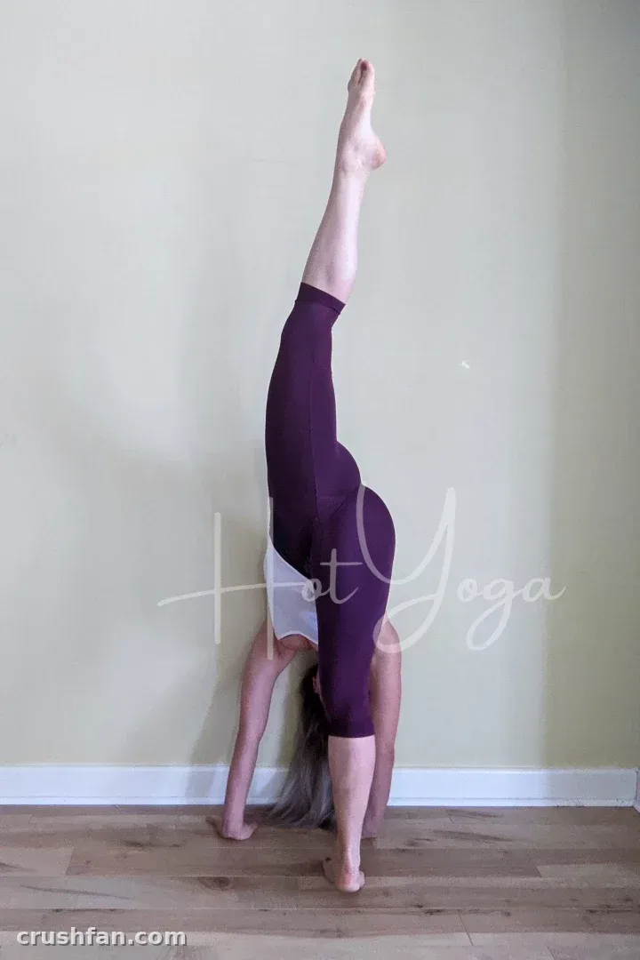 Creator in white top and purple leggings holding a handstand against a beige wall.