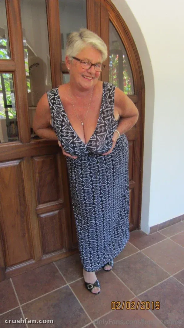 Fungrannies com um vestido maxi estampado em preto e branco em pé junto a portas de madeira.