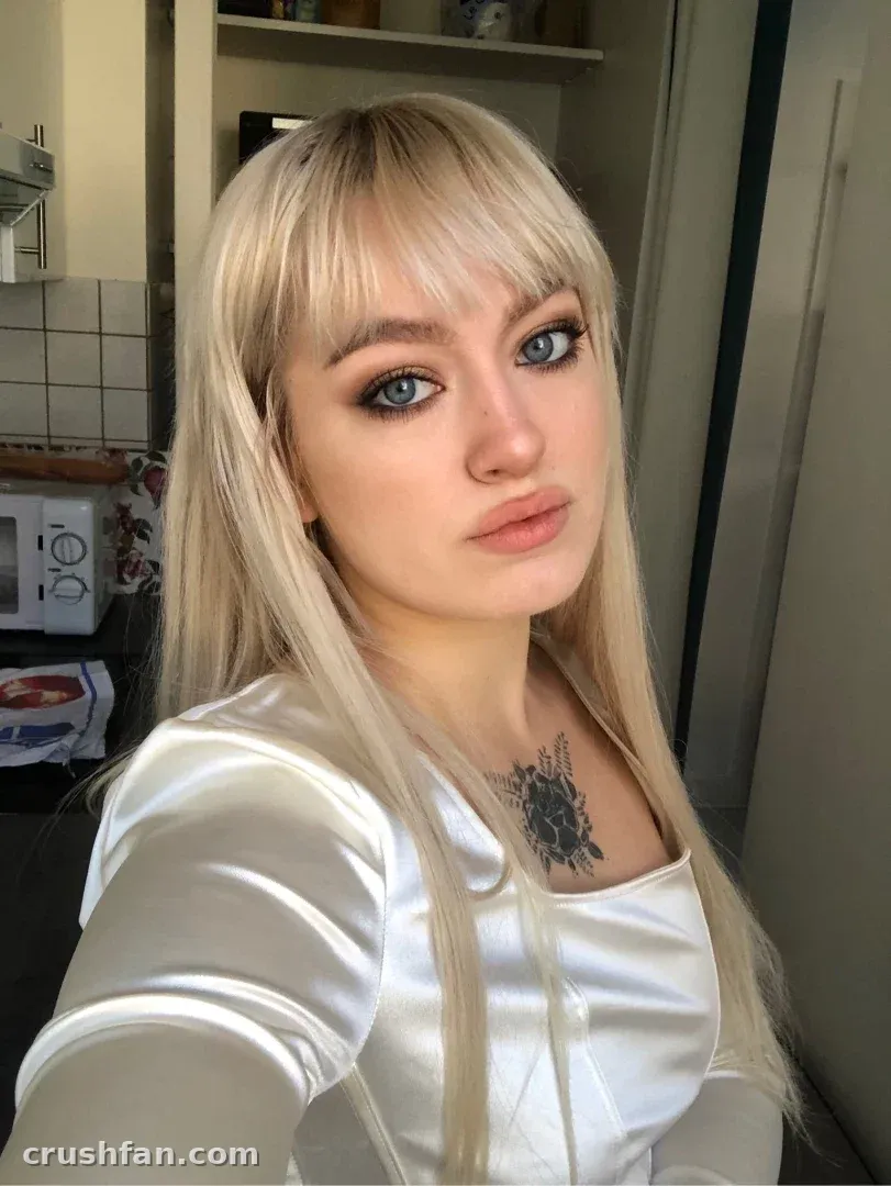 Creadora con un top de satén claro tomándose una selfie cercana en una cocina alicatada.
