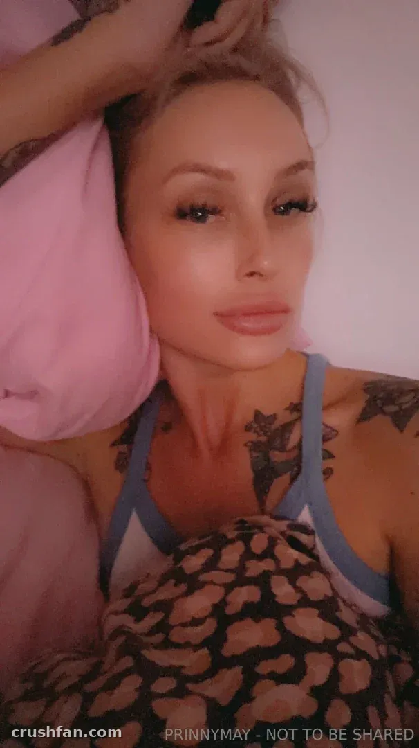 Prinny May taking a selfie in a pink bedroom with a leopard-print blanket.