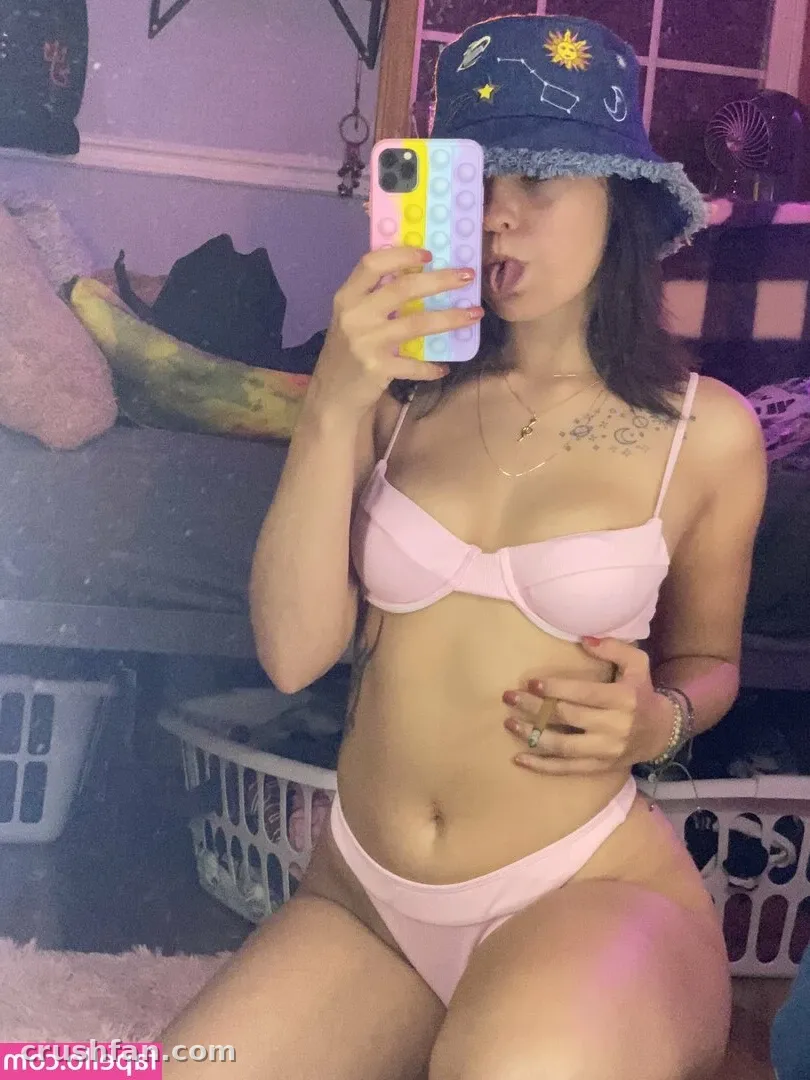 Créatrice en bikini rose et bob en jean prenant un selfie miroir dans une pièce éclairée en violet