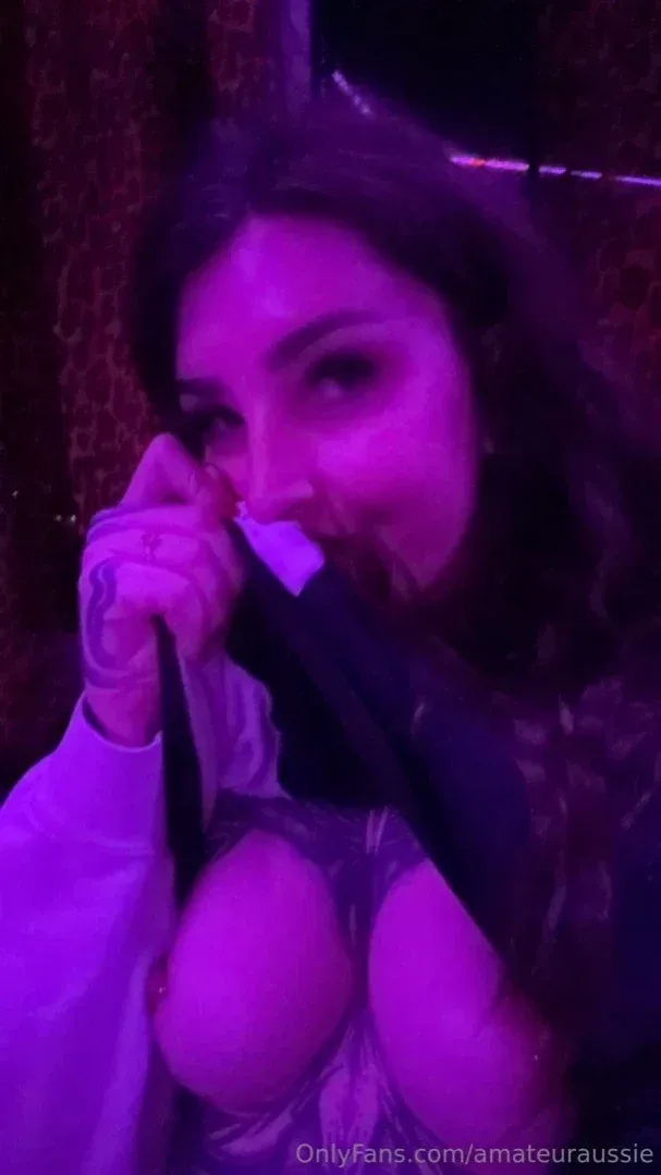 Aus Sarah segurando um microfone sob luz roxa