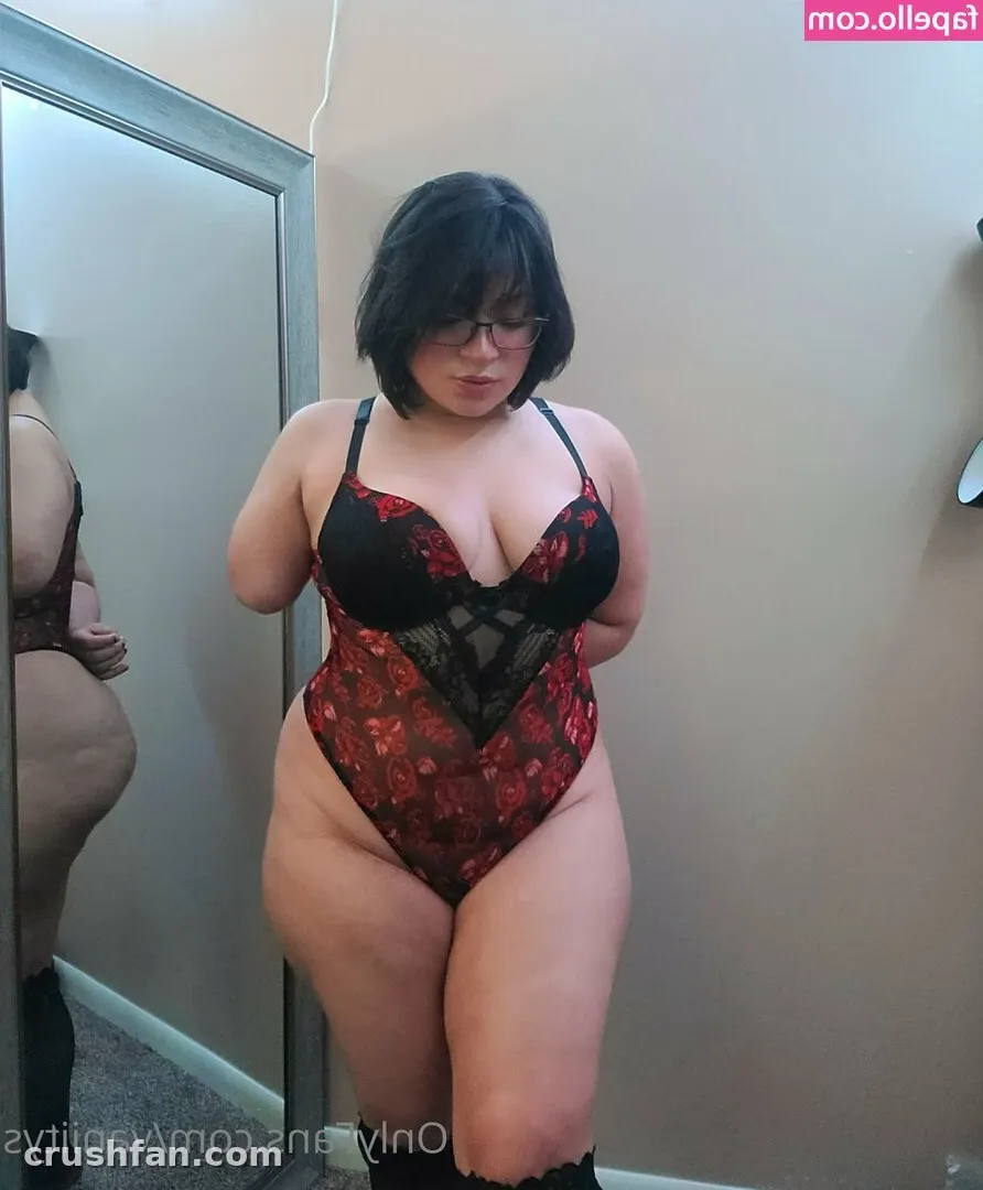 Vaniity con un body de encaje floral rojo y negro posando frente a un espejo