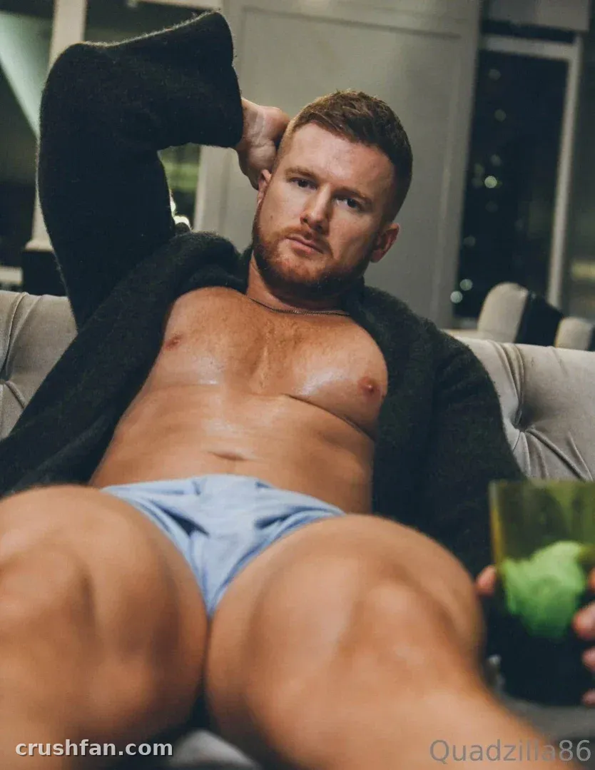 Quadzilla86 reclining on a sofa in an open dark cardigan with a drink in hand