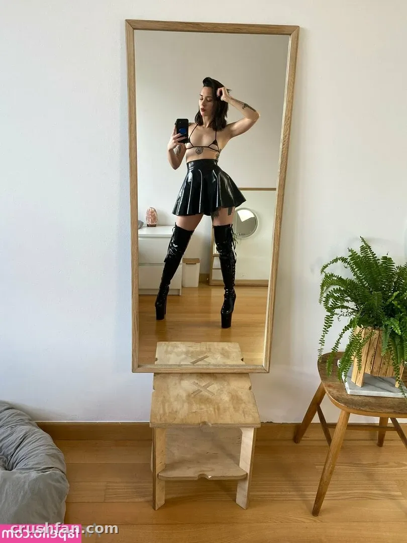 AnaKatana taking a mirror selfie in a glossy black outfit and knee-high boots.