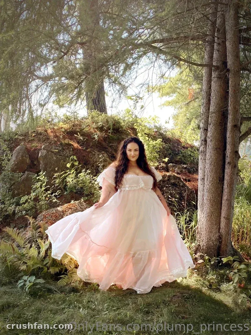 Creator em um vestido claro e esvoaçante em uma clareira na floresta iluminada pelo sol
