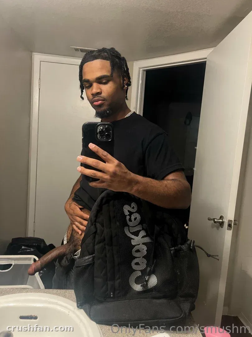 Creadora con camiseta negra tomándose una selfie frente al espejo con una mochila negra en primer plano.