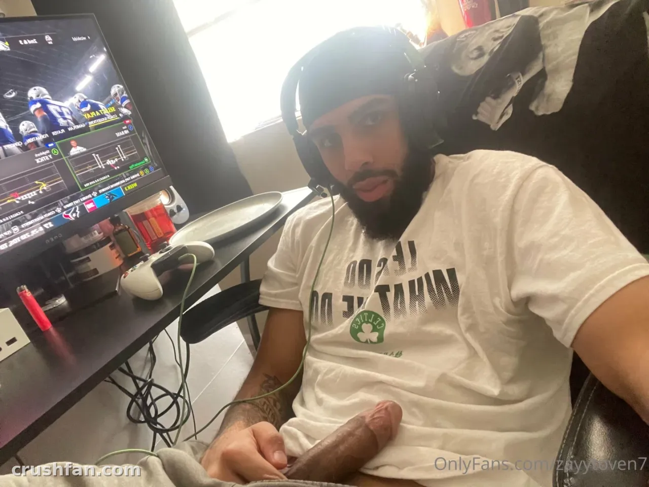 Zayytoven7 in a white tee and beanie sitting at a gaming desk with a monitor and controller.