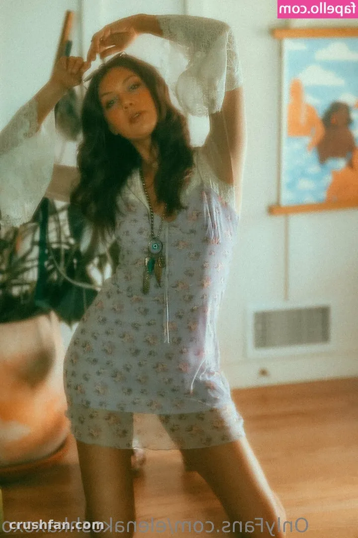 Elena Koshka in a floral dress and sheer white top posing indoors