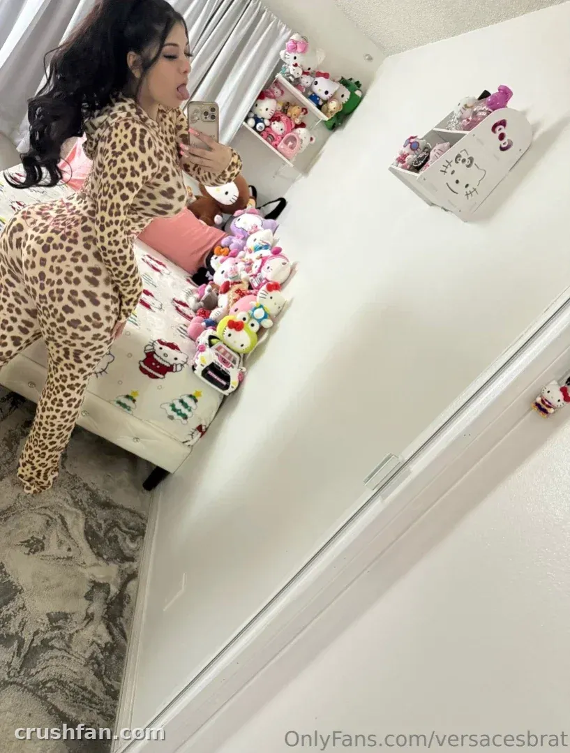 Cherry con un conjunto de estampado de leopardo tomándose una selfie en el espejo en una habitación con peluches