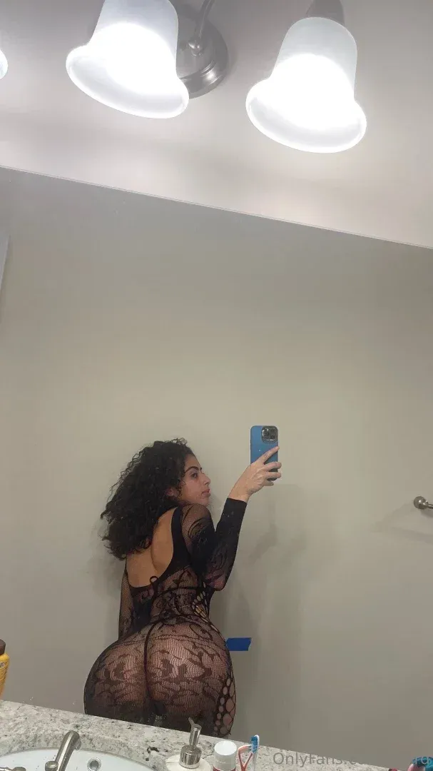 Ash in einem schwarzen Spitzen-Bodysuit beim Spiegel-Selfie in einem hellen Badezimmer