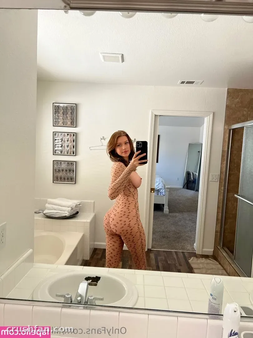 Creator in a patterned bodysuit taking a mirror selfie in a bright bathroom