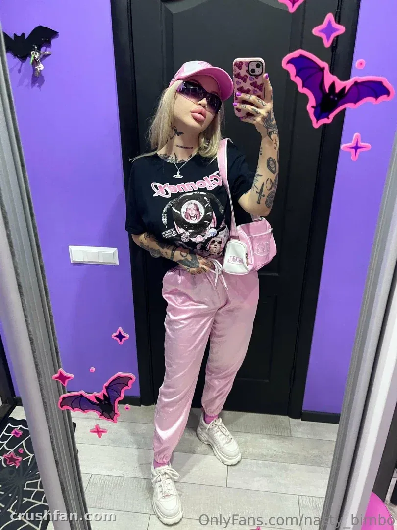 Créatrice en casquette rose et pantalon rose prenant un selfie miroir dans une pièce violette