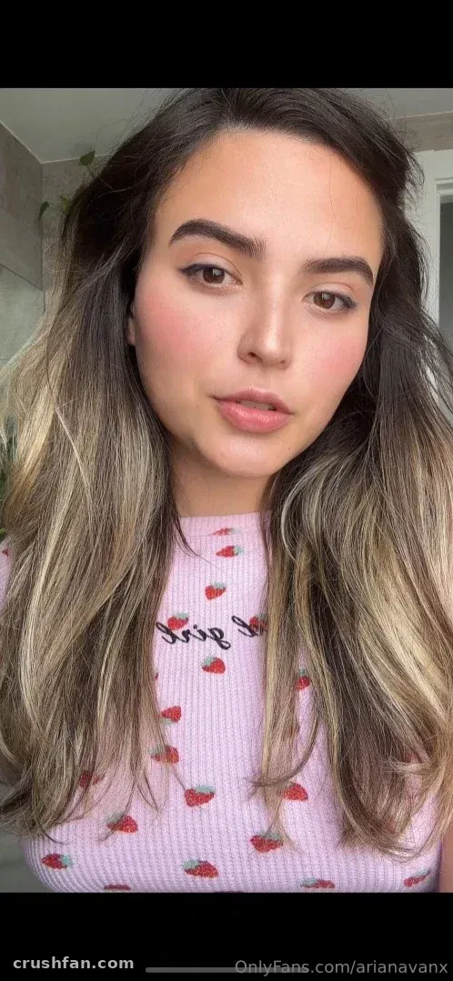 Ariana Van X con un top rosa estampado de fresas, mirando a la cámara con luz suave