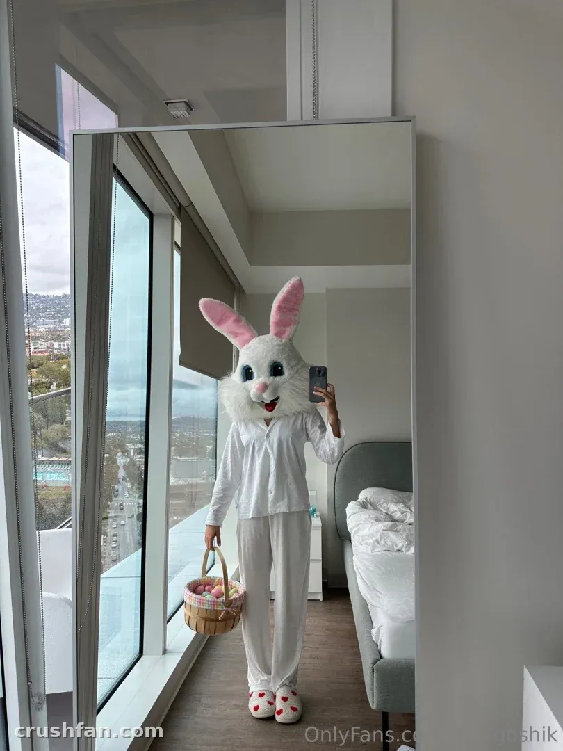 Anna in a white bunny mask and white loungewear taking a mirror selfie in a bright room