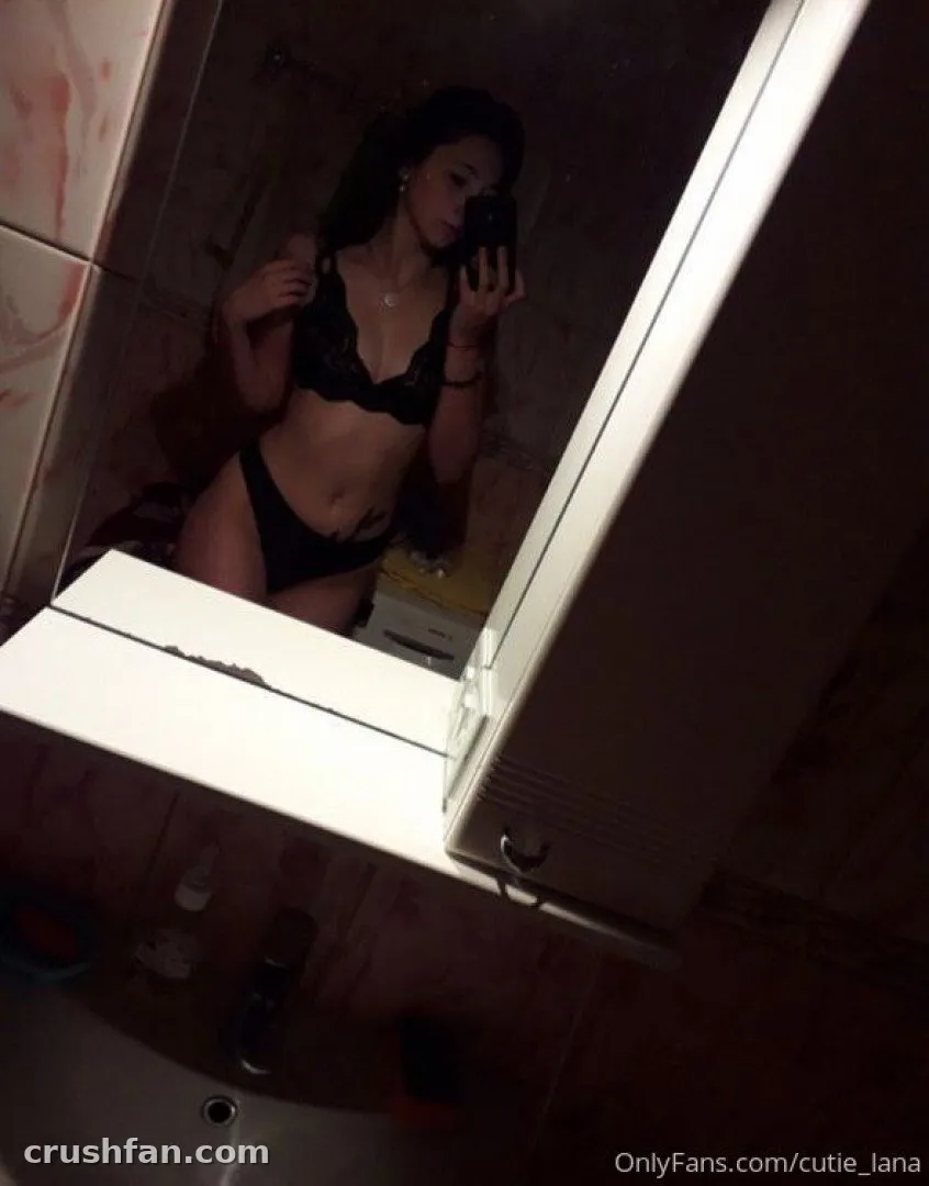 Cutie Lana in black lace lingerie taking a dim bathroom mirror selfie