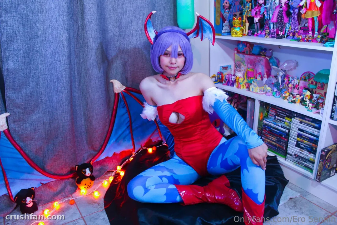 Cosplayer in a red and blue outfit with purple hair seated indoors near string lights