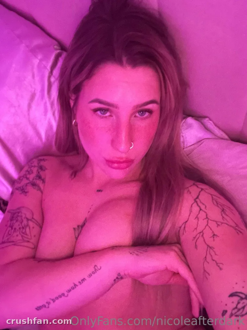 Nicole Garringer taking a pink-lit bedroom selfie with visible tattoos